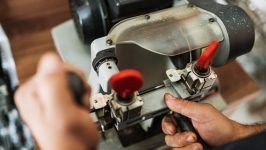 Close view of key copying machine with key. Duplicate machine make new key. Locksmith theme. Blank keys for cutting. Black modern car door opener.